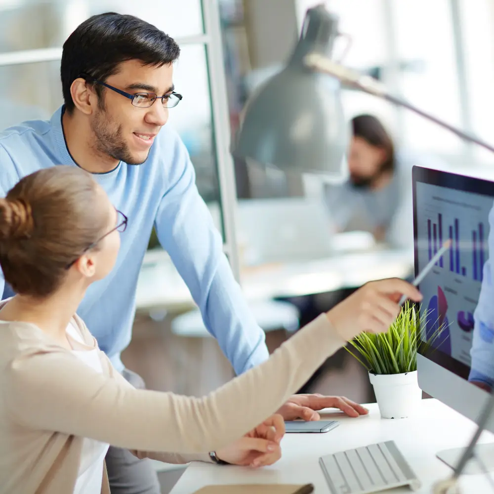 Frau erklärt Mann eine Grafik am Bildschirm