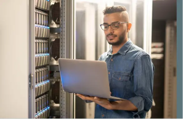 Mitarbeitender mit Laptop neben Akten